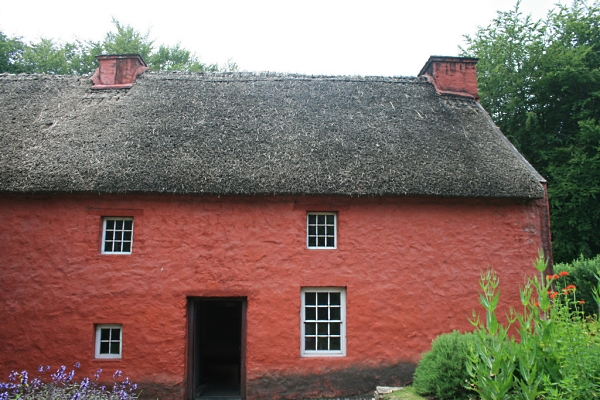 Thatched house with stone walls painted red